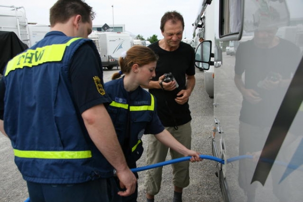 Eine Helferin des OV Friedrichshafen befüllt ein Wohnmobil mit Trinkwasser